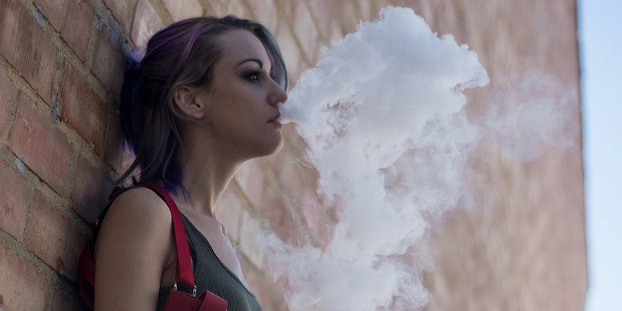 woman leaning on the wall while vaping